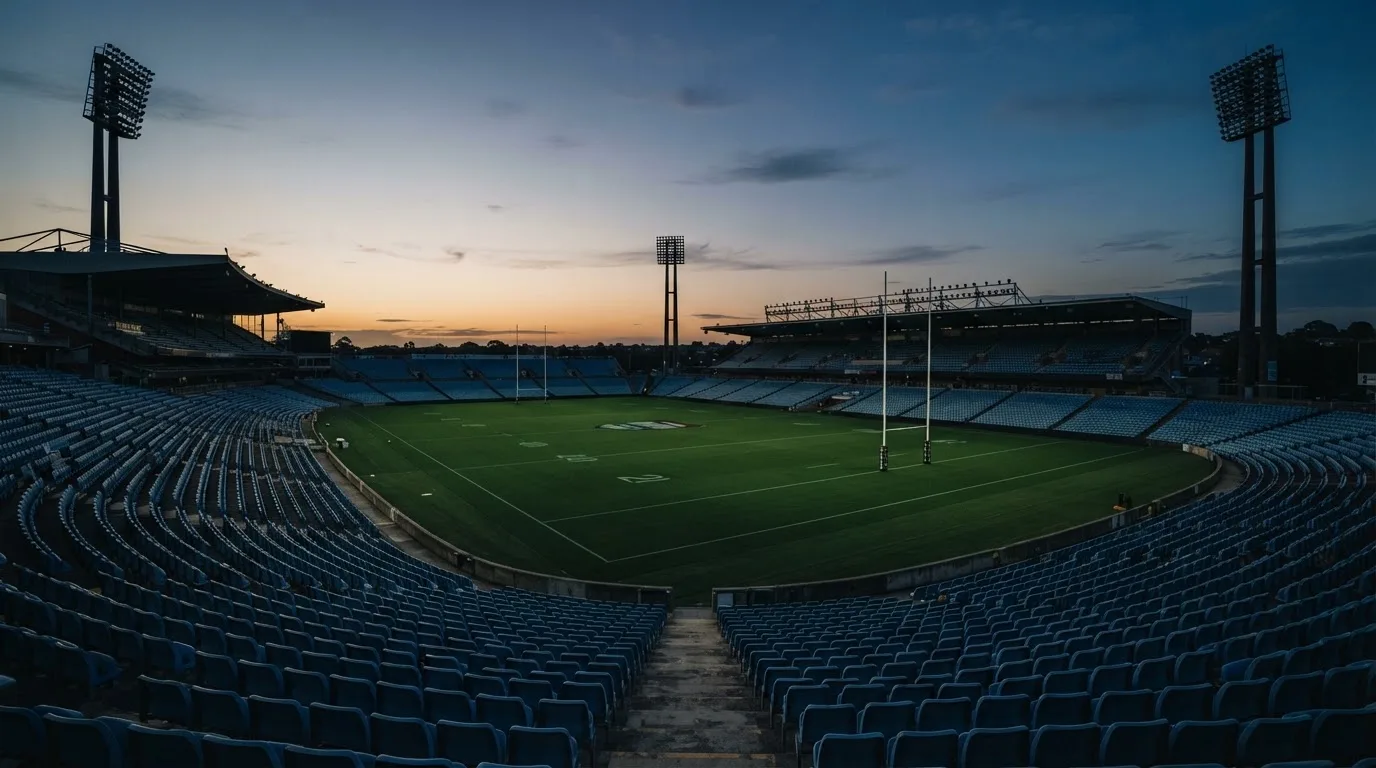 An empty football stadium with floodlight masts at dusk