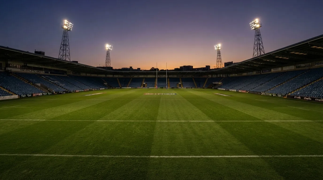 An empty football stadium with floodlight masts at dusk