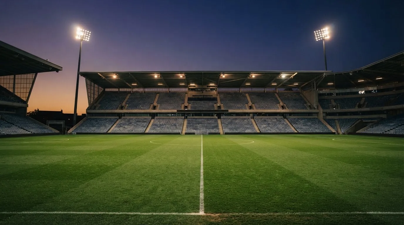 An empty football stadium with floodlight masts at dusk
