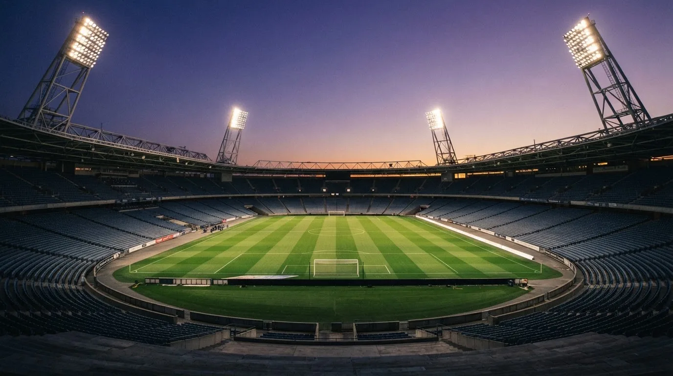 An empty football stadium with floodlight masts at dusk