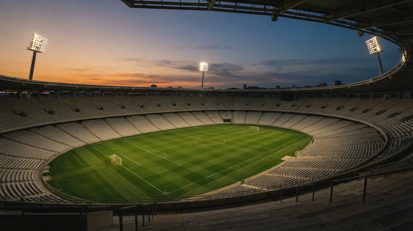 An empty football stadium with floodlight masts at dusk